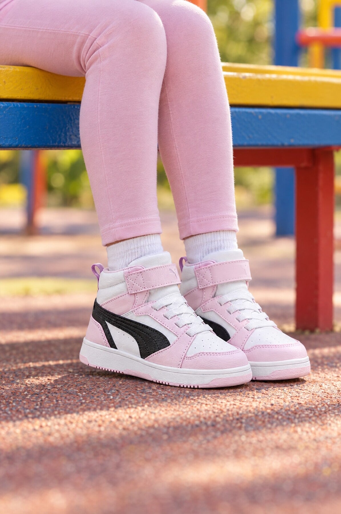 Puma Rebound V6 Mid pembe-beyaz çocuk sneaker, oyun parkında kız çocuğunun ayağında